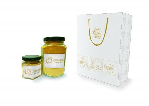 這張「」的照片是兩個玻璃瓶裝的黃色粉末，旁邊有一個白色紙袋，紙袋上印著一個卡通人物和一些烹飪的圖案。