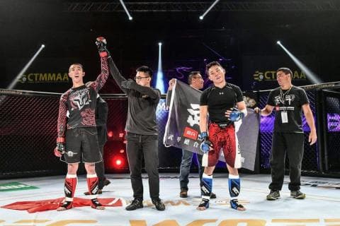 這張照片是幾位格鬥運動員在拳擊場比賽完畢後，舉起他們的雙手，慶祝勝利。其中一位格鬥運動員正在舉起他的冠軍腰帶。他們穿著格鬥服，站在拳擊場中央，背景是圍觀的觀眾和閃爍的燈光。