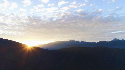 這張「日出」的照片是 山峰輪廓，和金色陽光灑落在雲層中的景象。