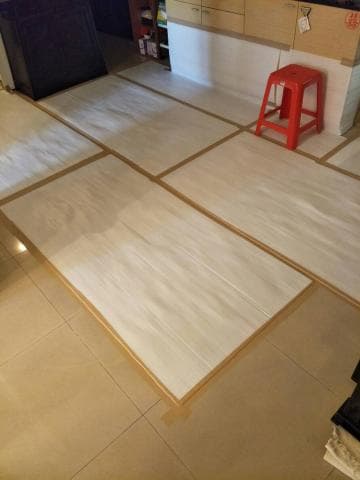 這張照片是地板上铺着几张用棕色胶带粘好的白色纸。