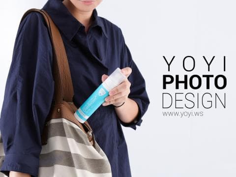 這張「產品宣傳」的照片是一個女人拿著一瓶護膚產品，背景是白色的，她的手提包上印著「YOYI PHOTO DESIGN」的字樣。