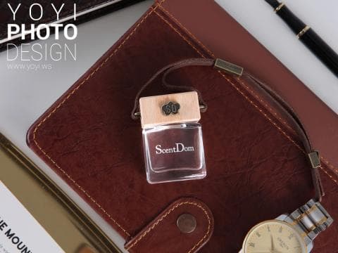 這張照片是一張棕色皮革筆記本，上面放著一個木頭和玻璃製成的香氛瓶，瓶身印有「ScentDom」字樣。