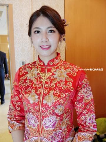 這張照片是一個穿著紅色旗袍的女性，她看起來很幸福。旗袍上精緻的花紋和亮片閃耀動人，更顯其優雅與美麗。