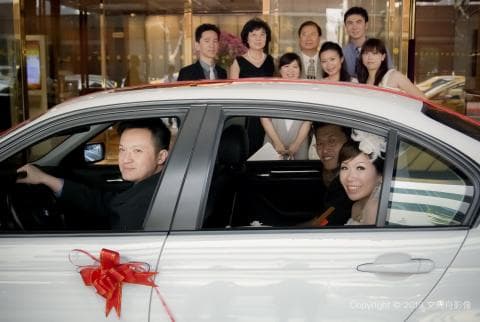 這張照片是一輛白色轎車，車內有新郎新娘和朋友，他們都很開心。