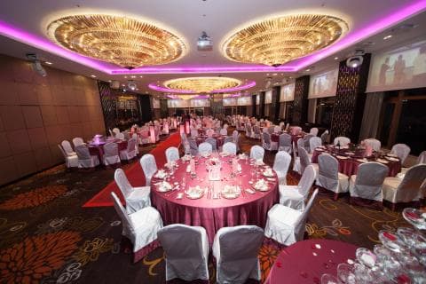 這張照片是一間婚宴會場，最顯眼的是中間擺放著精緻餐點的圓桌，周圍圍繞著白色椅套的椅子，營造出優雅浪漫的氛圍。