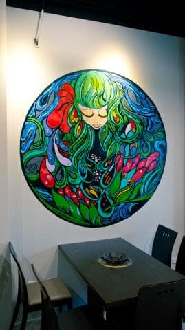 這張「牆上畫著一個圓形圖案，裡面是一個綠頭髮的女孩，周圍圍繞著許多花草」的照片是。