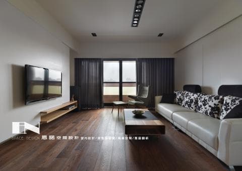 這張客廳的照片是一間現代化的公寓，配有大型電視、舒適的沙發和木地板。客廳的窗戶很大，可以看見戶外景觀。