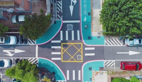 這張照片是一個十字路口，路口中間有一個黃色的標誌，路口周圍有許多汽車。