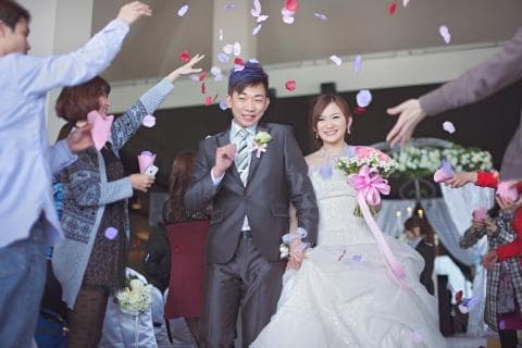 這張「婚禮」的照片是一對新人正在舉行婚禮儀式，新郎穿著西裝，新娘穿著婚紗，他們正被花瓣雨包圍，看起來十分幸福。