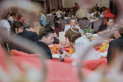 這張「婚禮」的照片是新郎新娘在婚宴上敬酒，他們坐在紅色的桌子上，周圍圍繞著親朋好友。