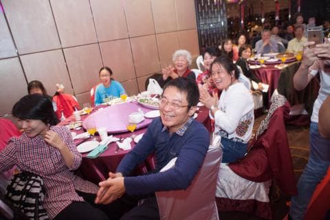 這張「聚餐」的照片是，一群人圍坐在一張圓桌旁，桌上擺滿了食物和飲料，他們看起來很開心。桌子周圍還擺放著一些椅子，人們圍坐在桌邊聊天，享受著美味的食物。