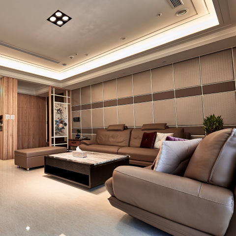 這張「現代客廳」的照片是，一個寬敞的空間，有沙發、咖啡桌和裝飾品。牆壁上有條紋的設計，天花板上有嵌入式照明。沙發上放著抱枕，咖啡桌上放著一個裝飾品。