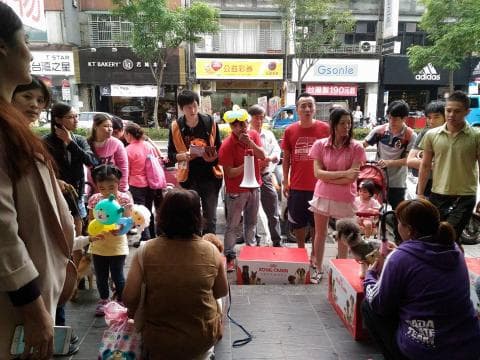 這張照片是一群人在街上逛街。照片中最重要的部分是照片左邊的小女孩，她拿著兩個藍色氣球，旁邊還有她的家人。