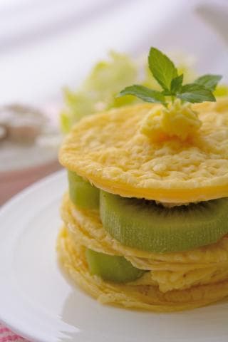 這張「鬆餅」的照片是，一層層的鬆餅中間夾著新鮮的奇異果，上面還放了一片薄薄的奶油，看起來非常美味。