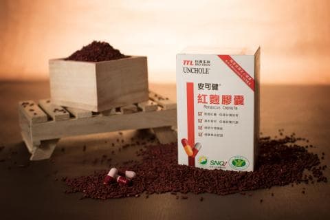 這張「紅麴膠囊」的照片是一個紅麴膠囊產品的廣告。照片中有紅麴顆粒、木盒、木架和紅麴膠囊。