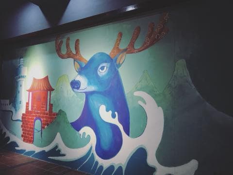 這張照片是一幅以藍色鹿為主題的壁畫。鹿的頭部朝左，鹿角很大，鹿的眼睛和嘴巴都畫得很生動。
