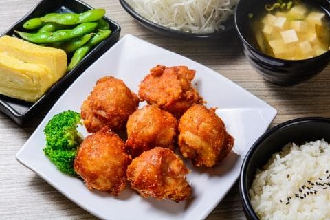 這張「日式炸雞」的照片是一盤香脆可口的日式炸雞，旁邊有白飯、味噌湯和綠色的毛豆，看起來非常美味。