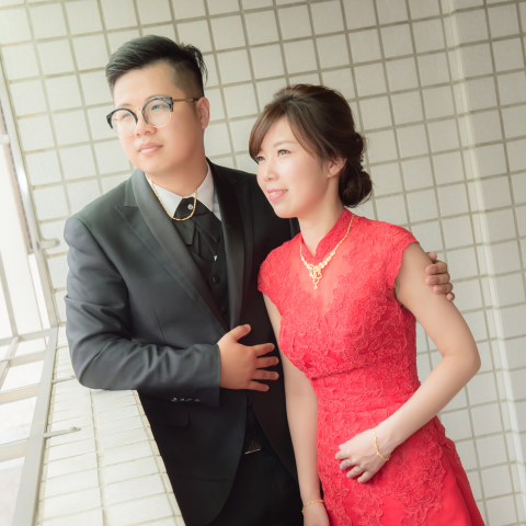 這張照片是一對新人婚紗照。新郎穿著黑色西裝，新娘穿著紅色旗袍，他們看起來很幸福。