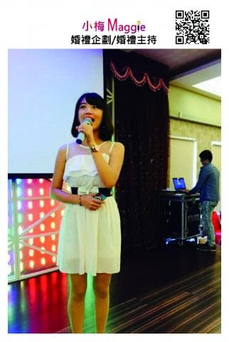 這張「Maggie」的照片是她在臺上唱歌，她穿著白色的洋裝，手拿麥克風，看起來很開心。