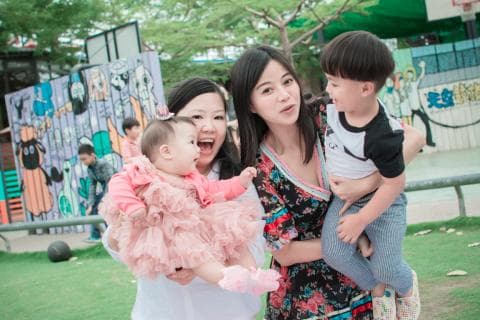 這張照片是三位女性和一個男孩，其中最小的女孩穿著粉色洋裝，由一位女性抱著，女孩的左手放在抱著她的女性的肩上。