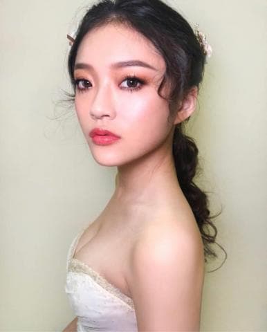 這張「新娘」的照片是一名女子，她身穿白色禮服，頭髮盤成髮髻，妝容精緻，看起來非常漂亮。