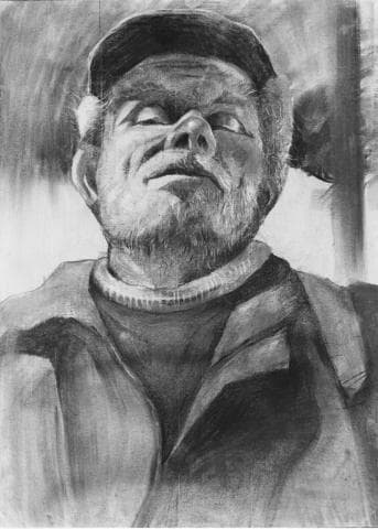 這張照片是一個男人的肖像，他穿著一件厚重的夾克，頭戴著一頂帽子，臉上有一點鬍子，眼睛向上望著。