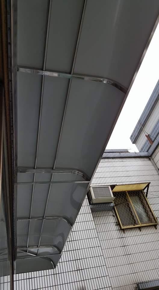 這張「遮雨棚」的照片是一個安裝在房屋外牆的遮雨棚，它由金屬製成，並帶有弧形設計，可以有效地遮擋雨水。
