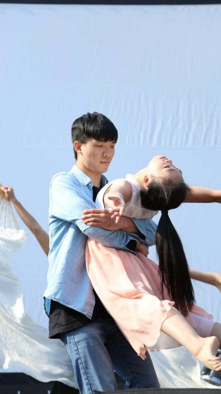 1) 照片顯示一個男生抱著一個女生，女生穿著粉紅色的洋裝，男生穿著藍色的襯衫和牛仔褲