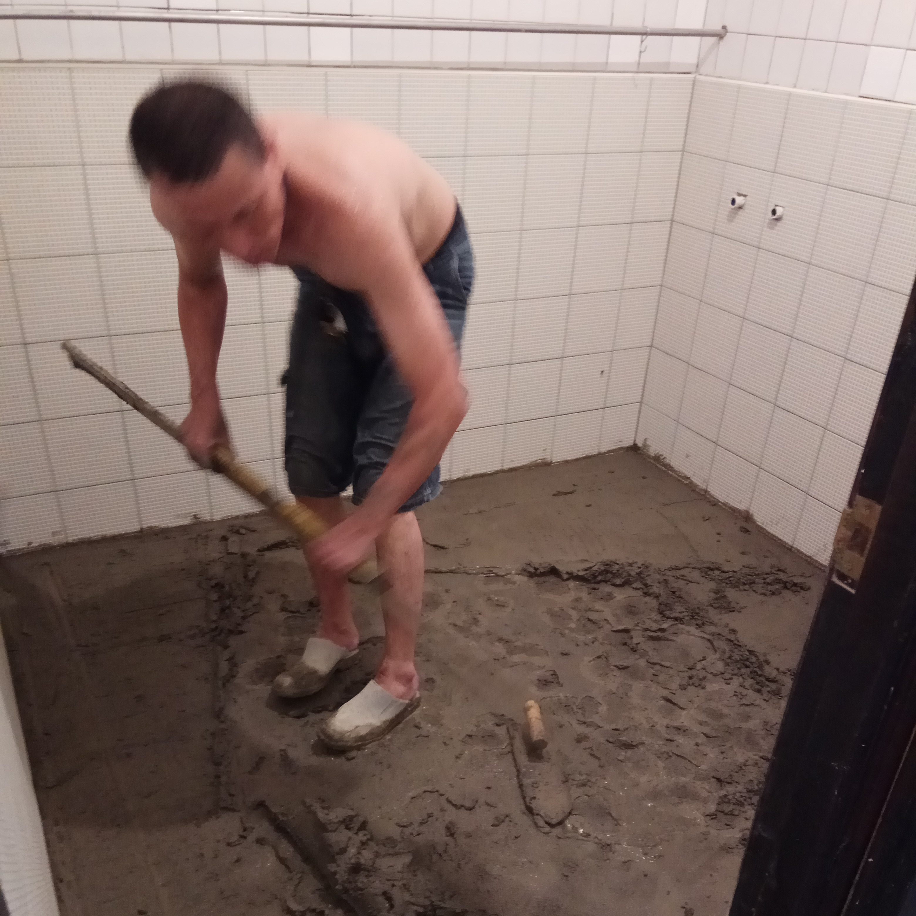 1) 照片顯示一名男子在浴室地板上進行泥作