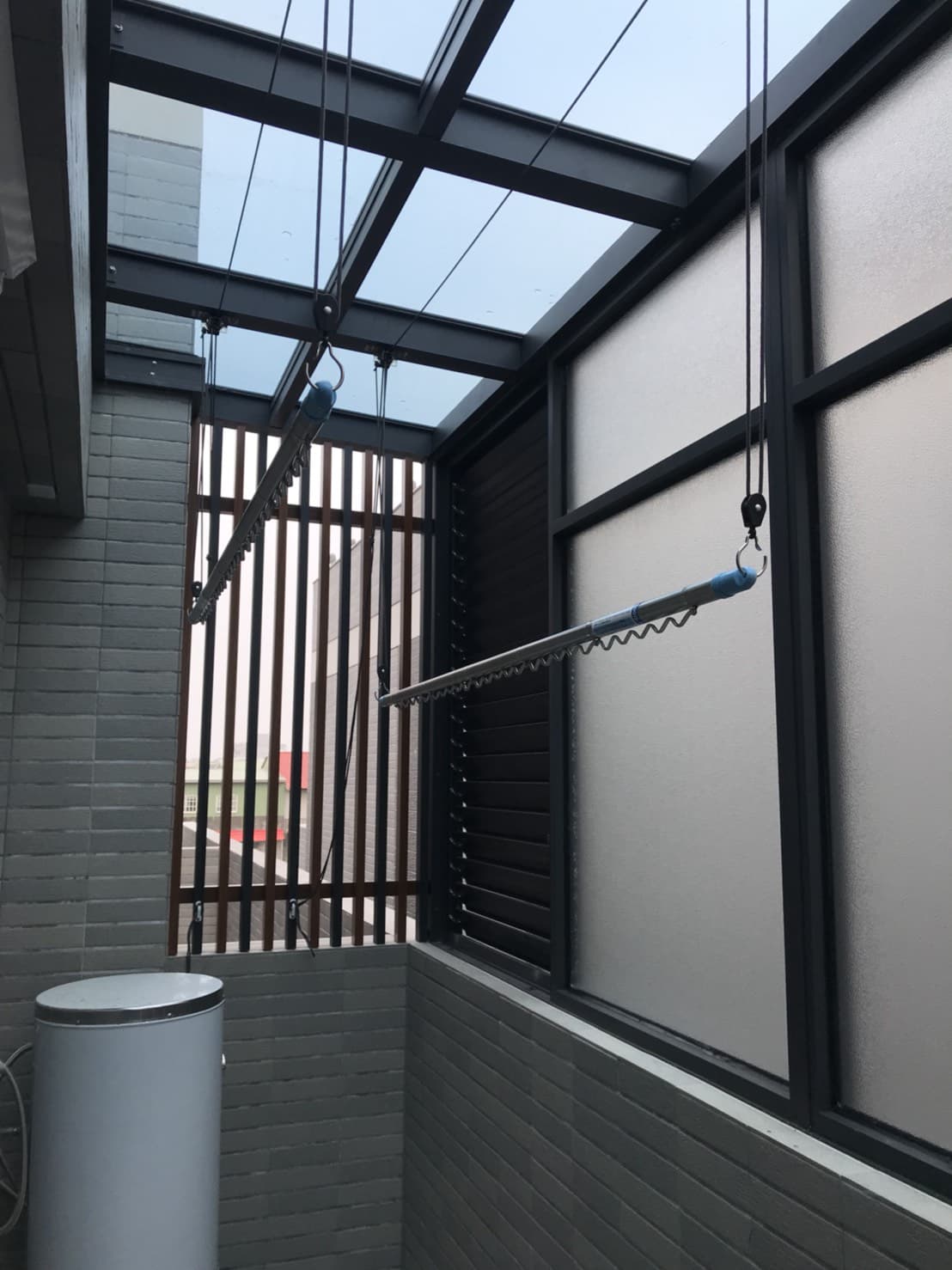 1. 照片顯示一個陽台，陽台上有一個晾衣架，晾衣架上有兩條繩子，繩子上掛著一根金屬桿，金屬桿上可以掛衣服