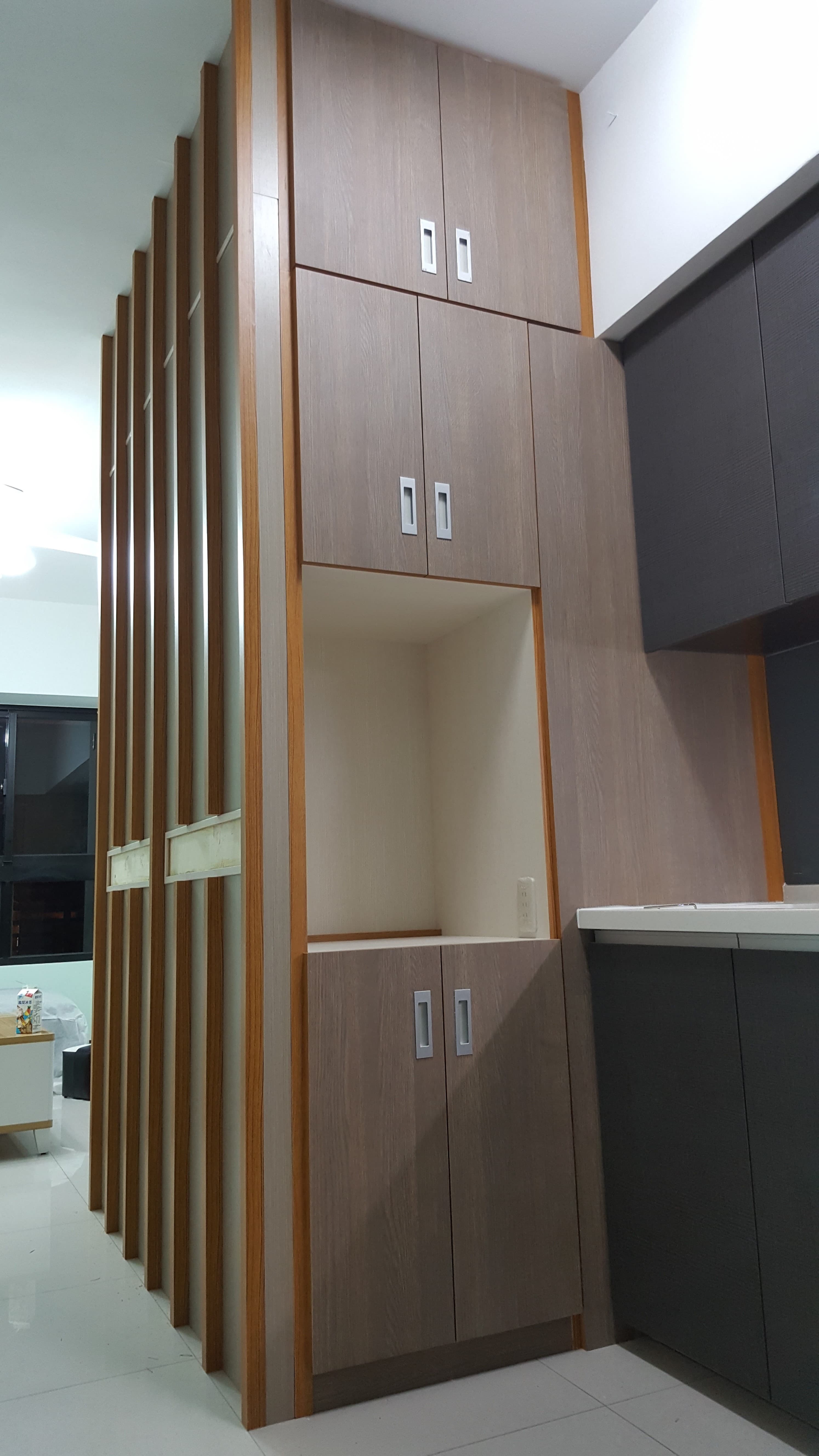 這張照片是一個現代化的廚房，最重要的是牆上的木質櫥櫃，有三個橫排的抽屜，以及一個下方的兩層櫃子，櫃子上方還有個開放式收納空間，整体设计简约大方。 
