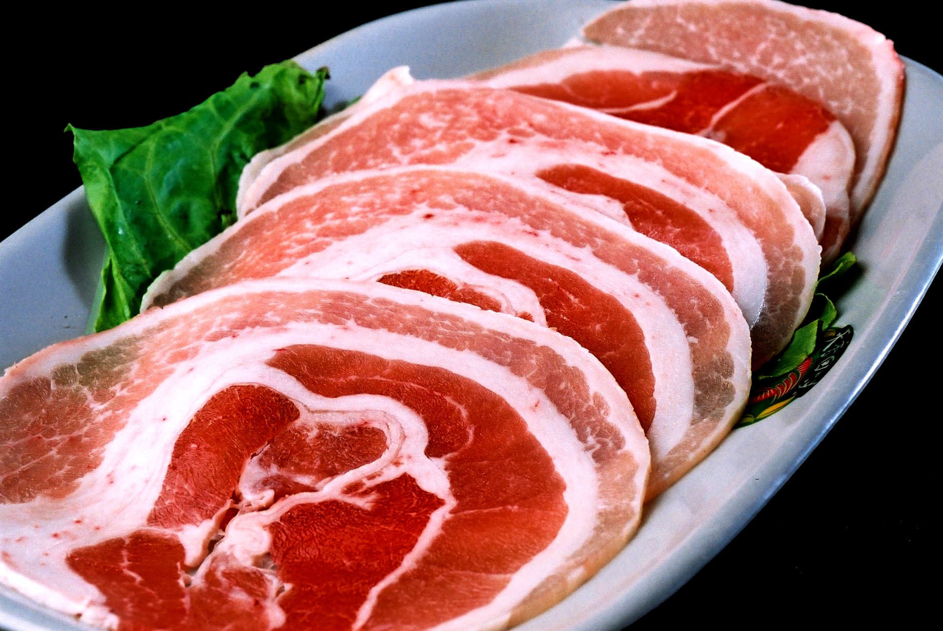 這張照片是一盤生肉，看起來像是豬肉，肉片排列整齊，最下面那塊肉的紋理清晰可見。