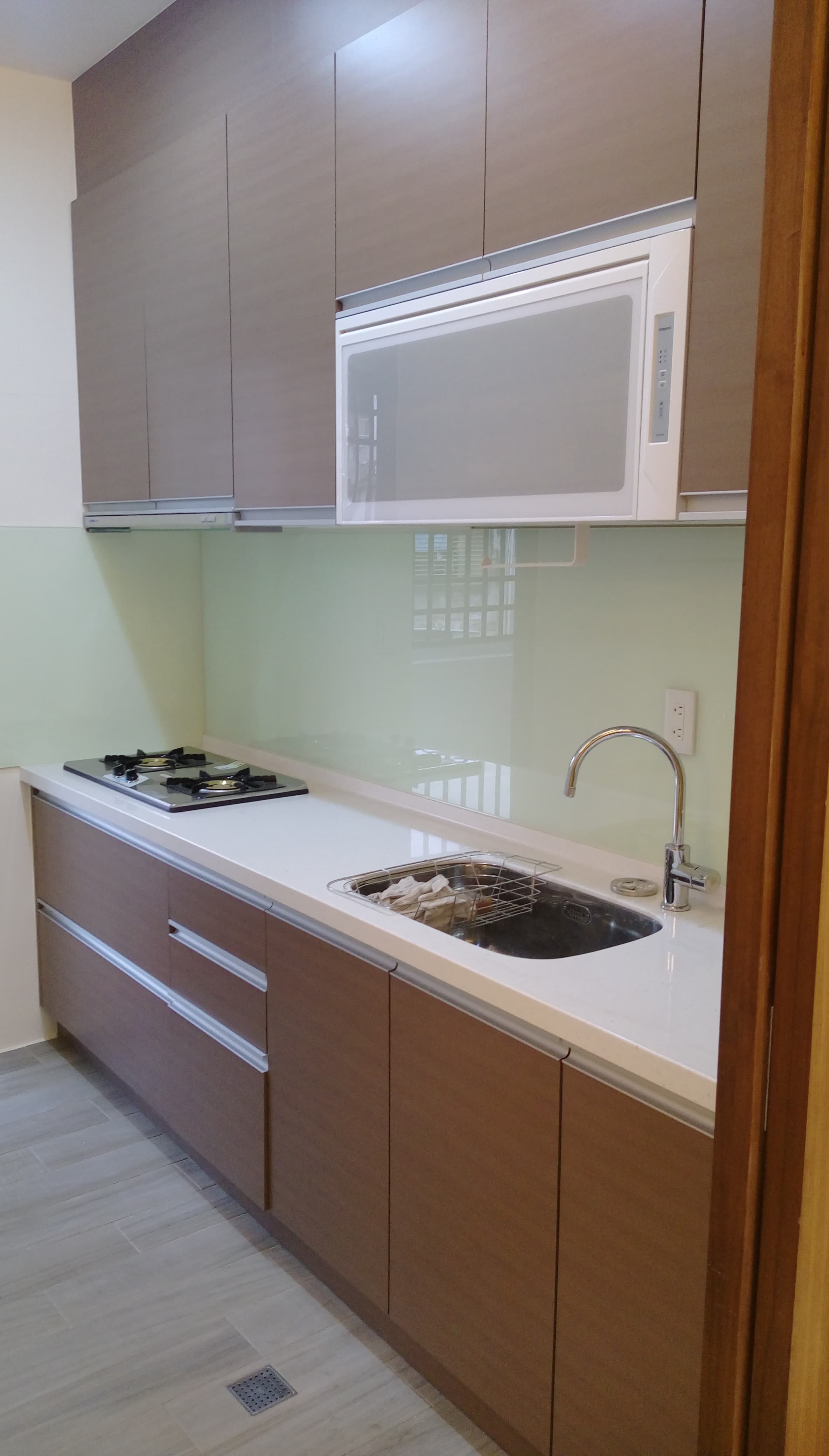 1) 照片顯示一個木製廚房，帶有白色檯面、水槽和瓦斯爐，以及一個白色壁櫥