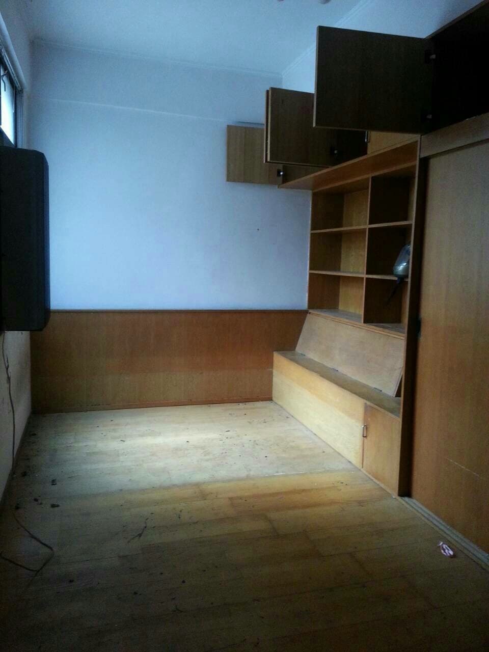 1) 這張照片顯示一個房間，其中有一個木板床架、一個大型衣櫃和一個架子