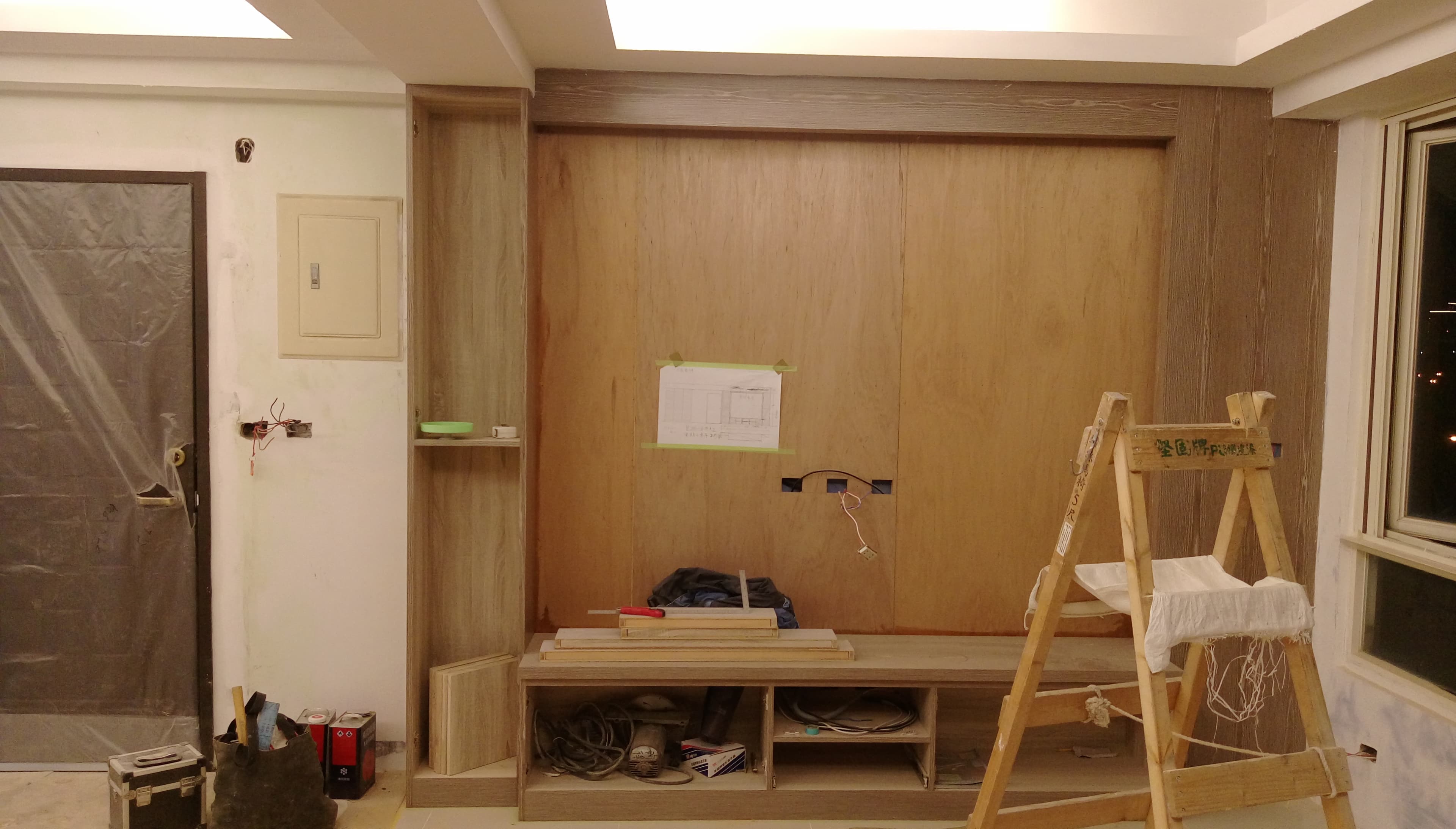 這張照片是一個裝修中的房間，最顯眼的是牆上裝飾著木板，木板上有著一些工具和木板，暗示著房間正在裝修。