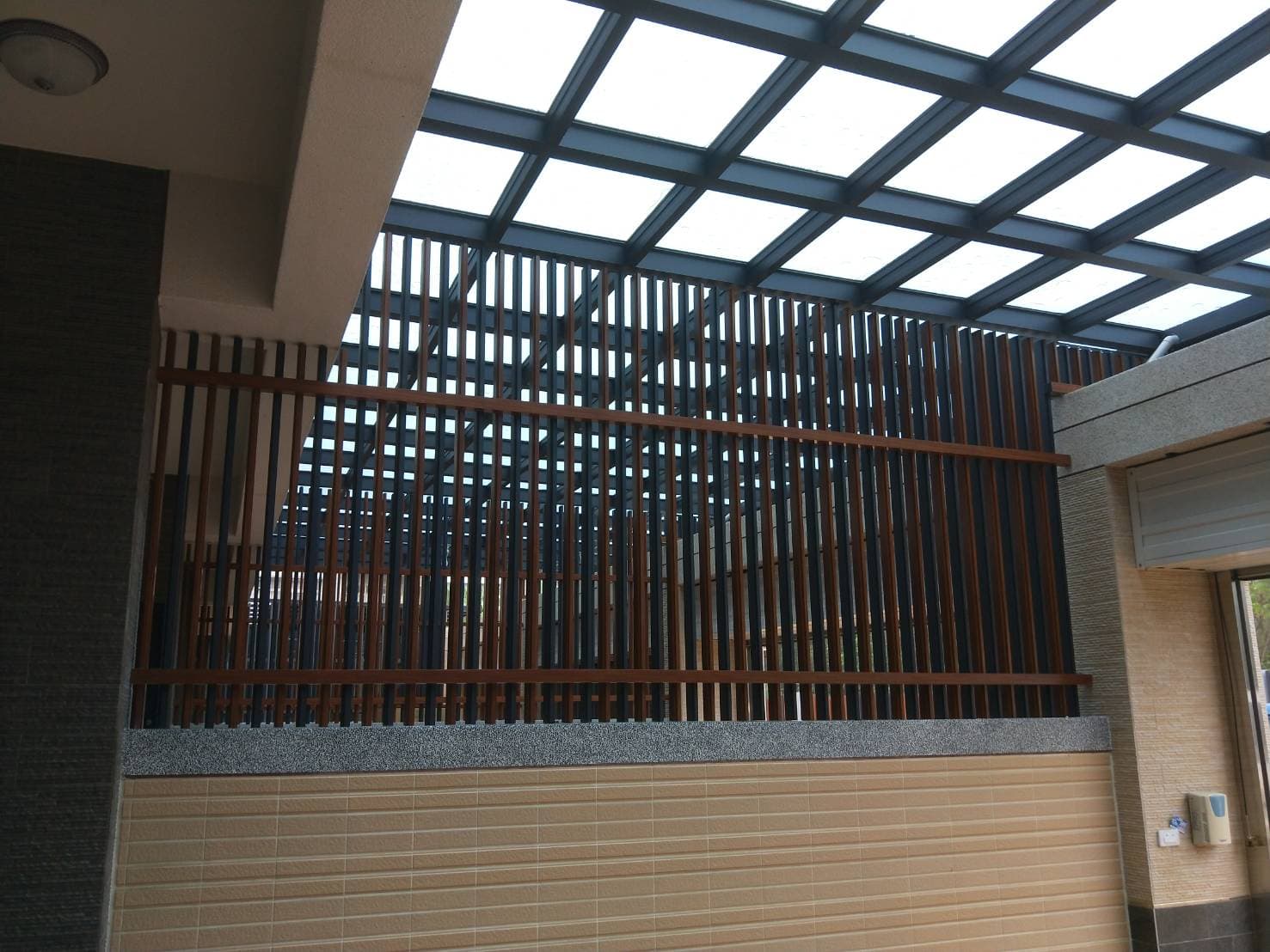 這張「建築物外觀」的照片是一個帶有玻璃屋頂的建築物。屋頂上的玻璃呈現格狀,而建築物外牆則使用木條建造的圍籬。