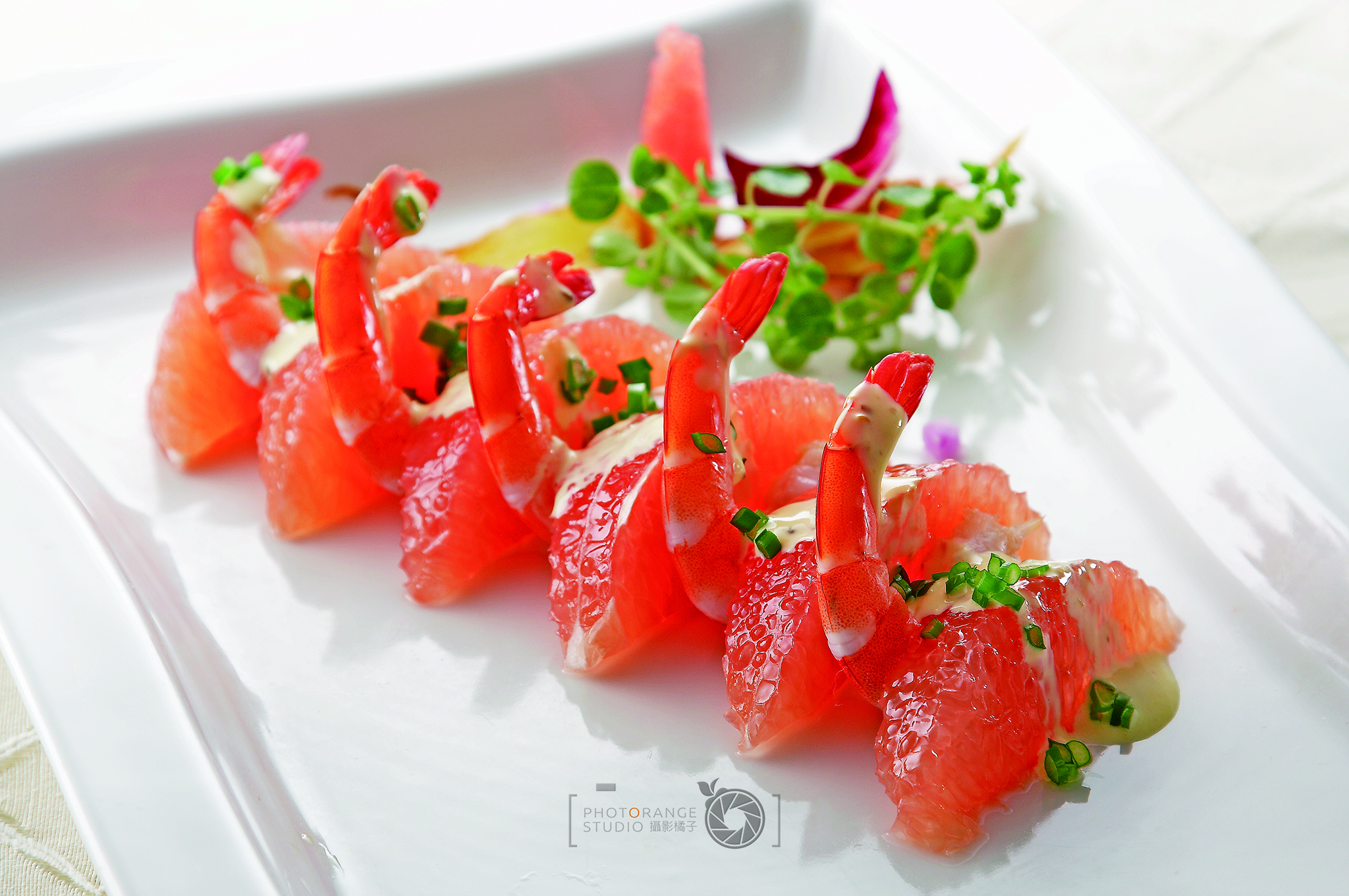 這張「蝦仁沙拉」的照片是幾片紅色的橘子上面放著蝦仁和香菜，看起來很美味。