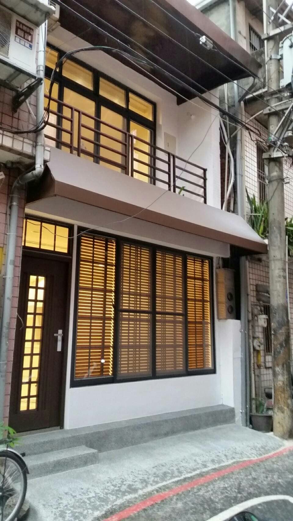 1) 照片顯示一間有陽台的房子，陽台上有欄杆，房子外觀看起來是現代風格，外牆是白色，門窗是深棕色