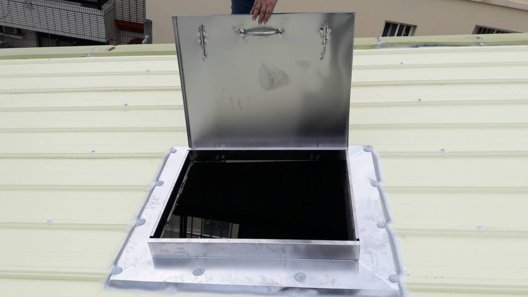 這張「屋頂」的照片是一個打開的屋頂天窗，它是由金屬製成，並有一個把手。