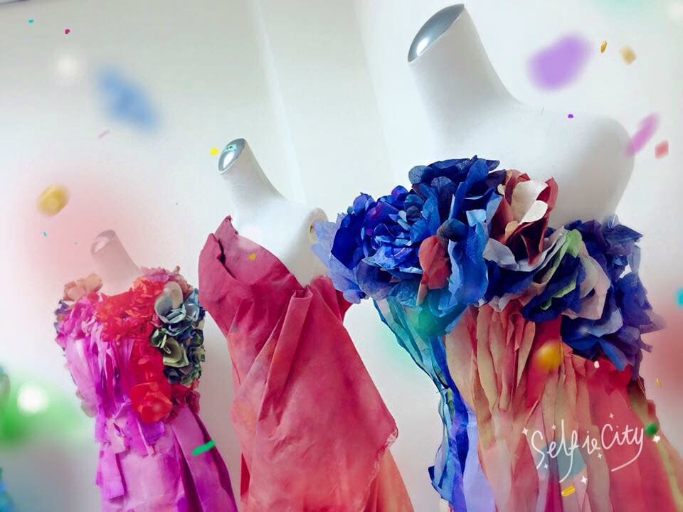 這張「三件手工禮服」的照片是，三件禮服都以花瓣作為裝飾，分別是紅色、粉色和藍色。