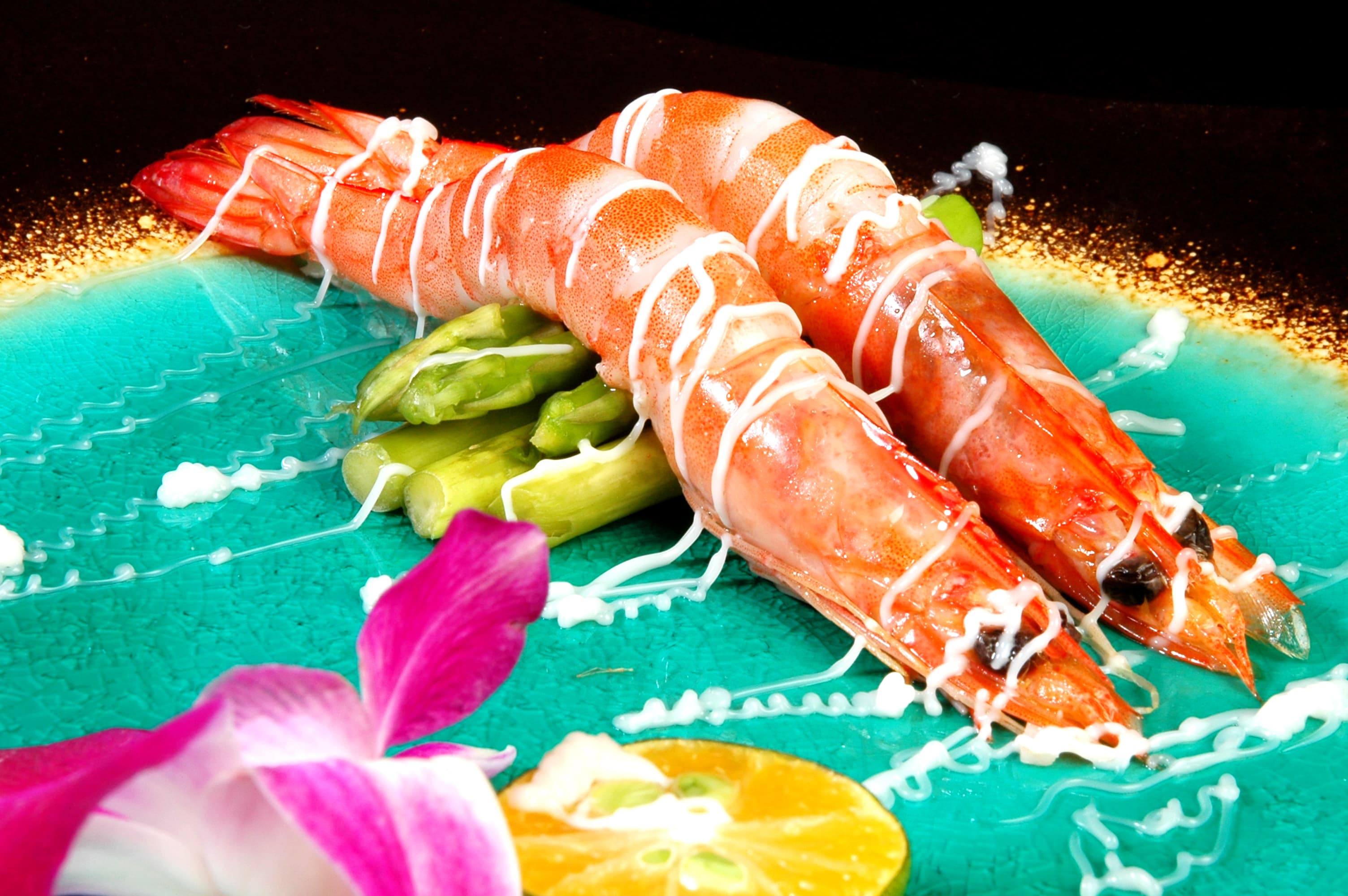 這張「蝦料理」的照片是兩隻蝦子，上面淋了白色醬汁，配上蘆筍，放在藍色的盤子上。