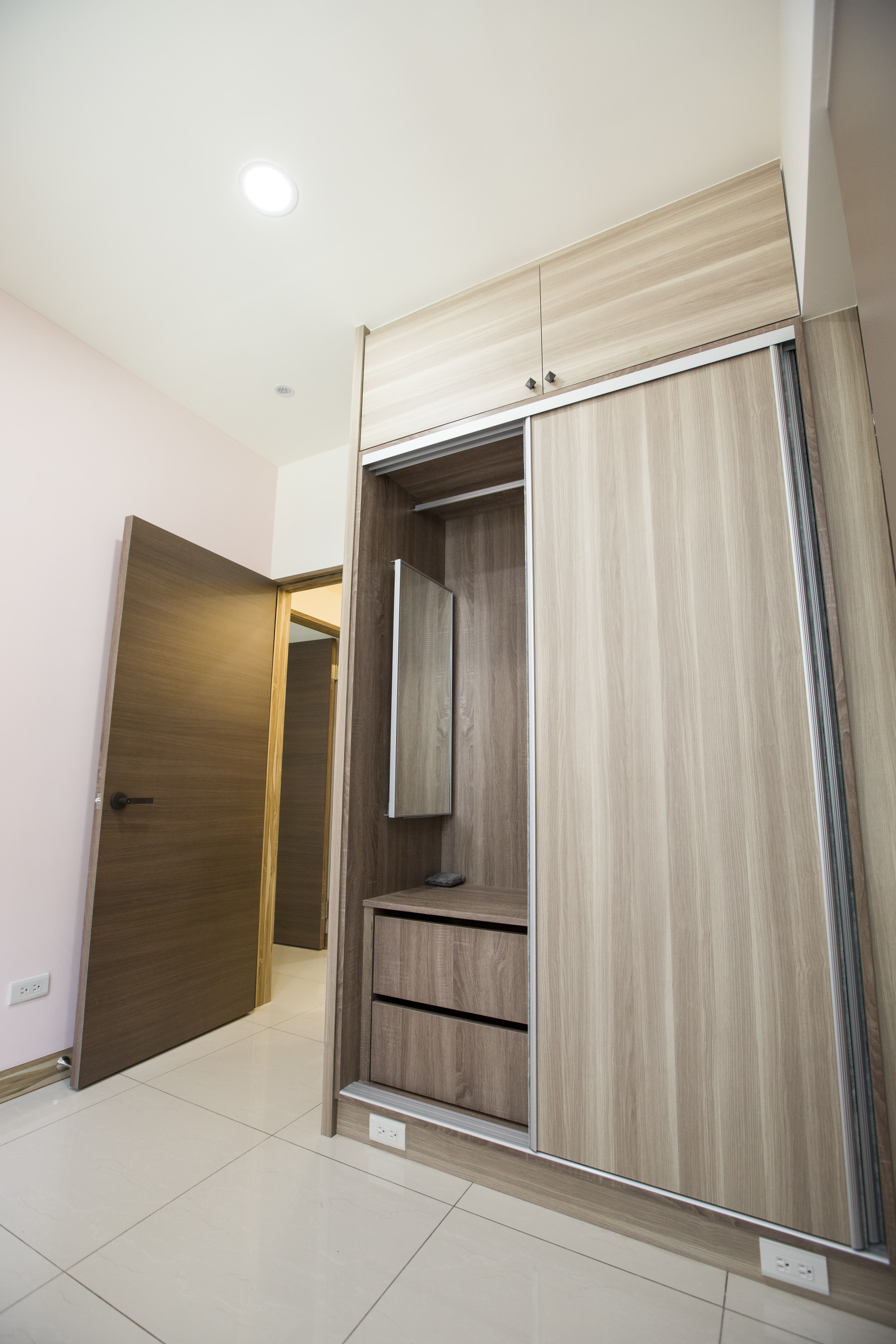 這張照片是一個帶有滑門衣櫃的臥室，衣櫃的設計時尚且簡潔，以木紋色為主，搭配白色牆面，營造出簡約舒適的氛圍。