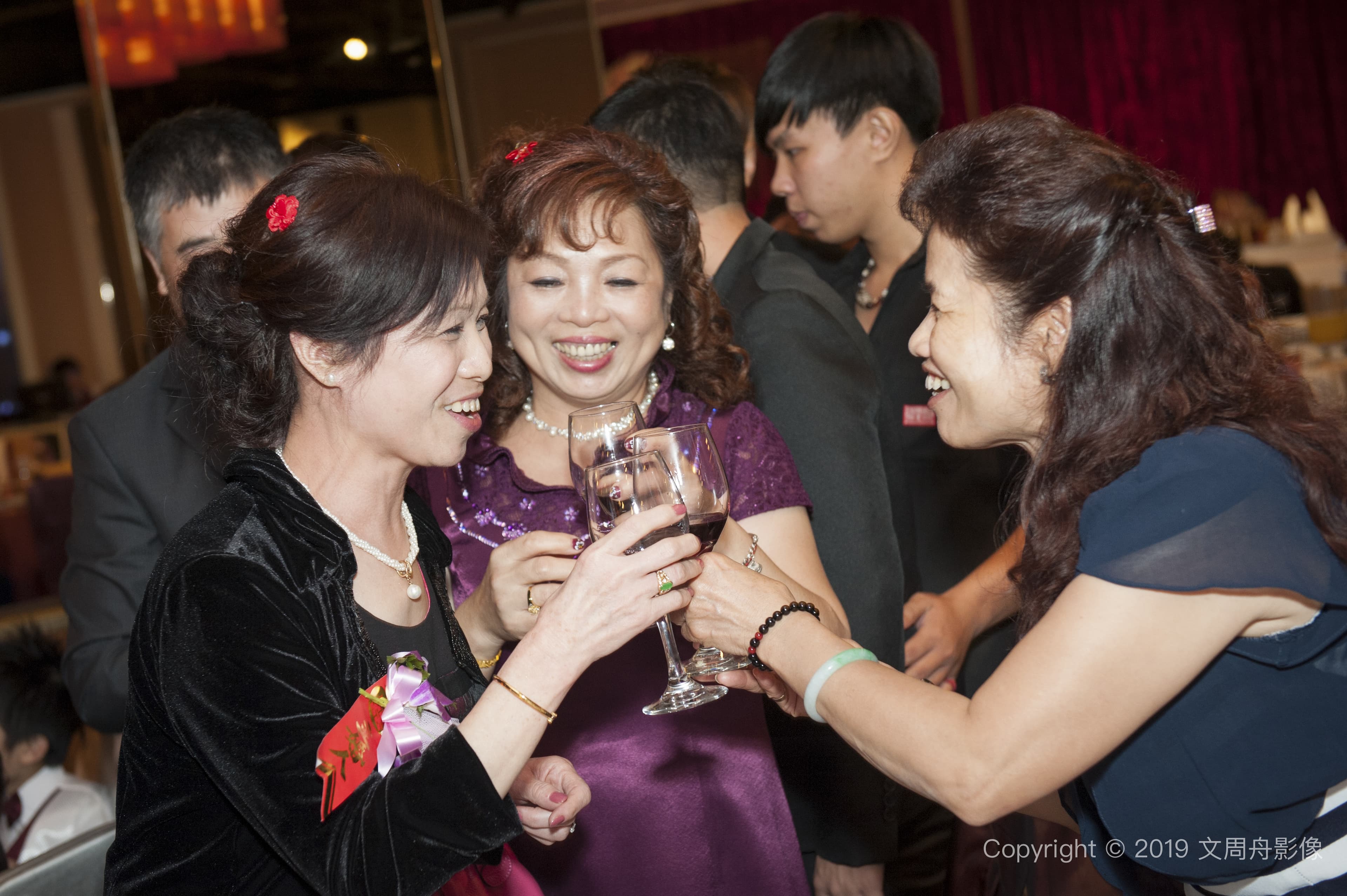 這張照片是一群朋友在餐廳聚會，其中一位女士舉著酒杯，準備和朋友乾杯。