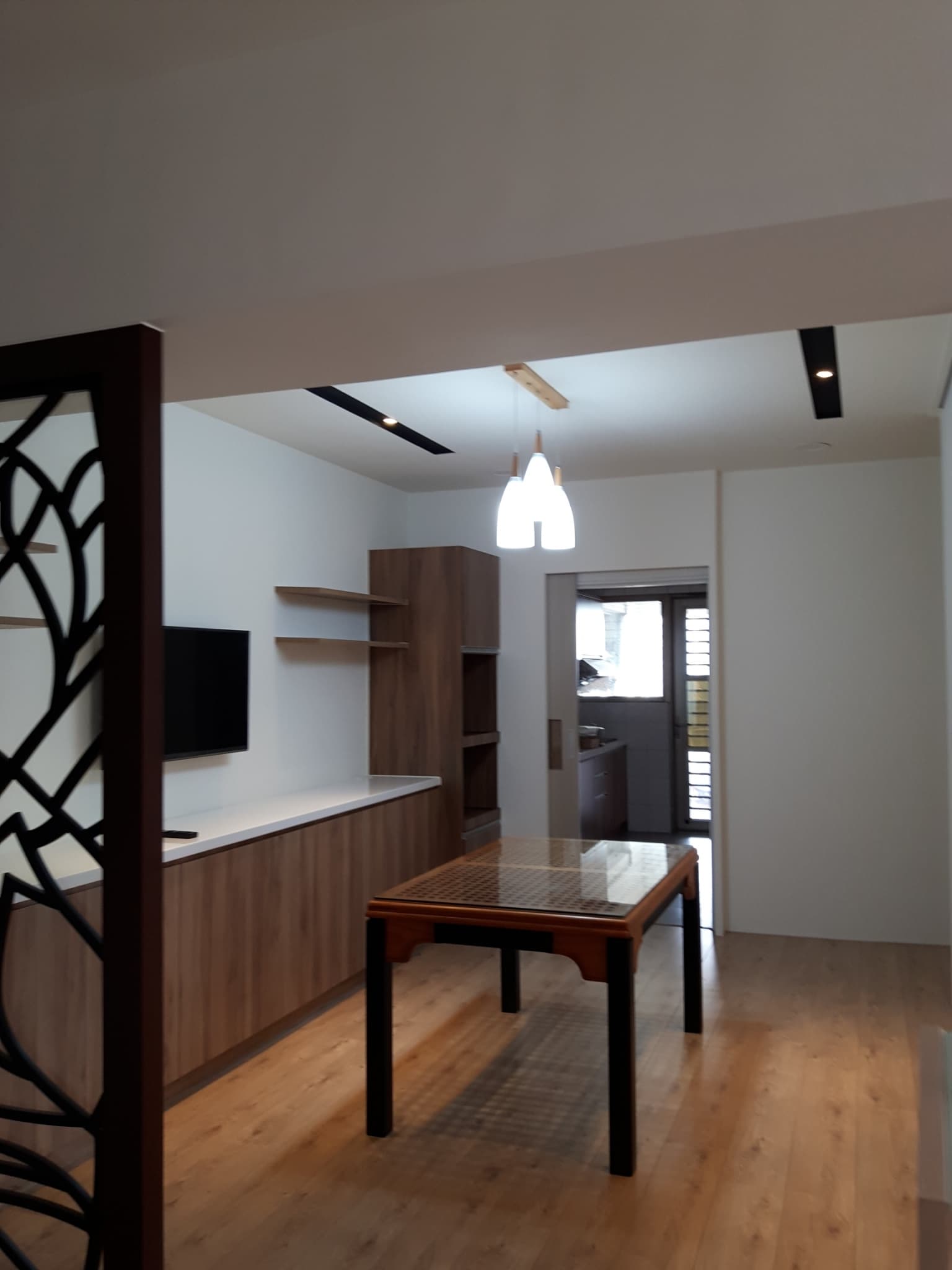 1) 照片顯示一個現代的客廳，有著木質地板和天花板，以及一個木質櫥櫃，一個黑色的桌子和一個木製的屏風