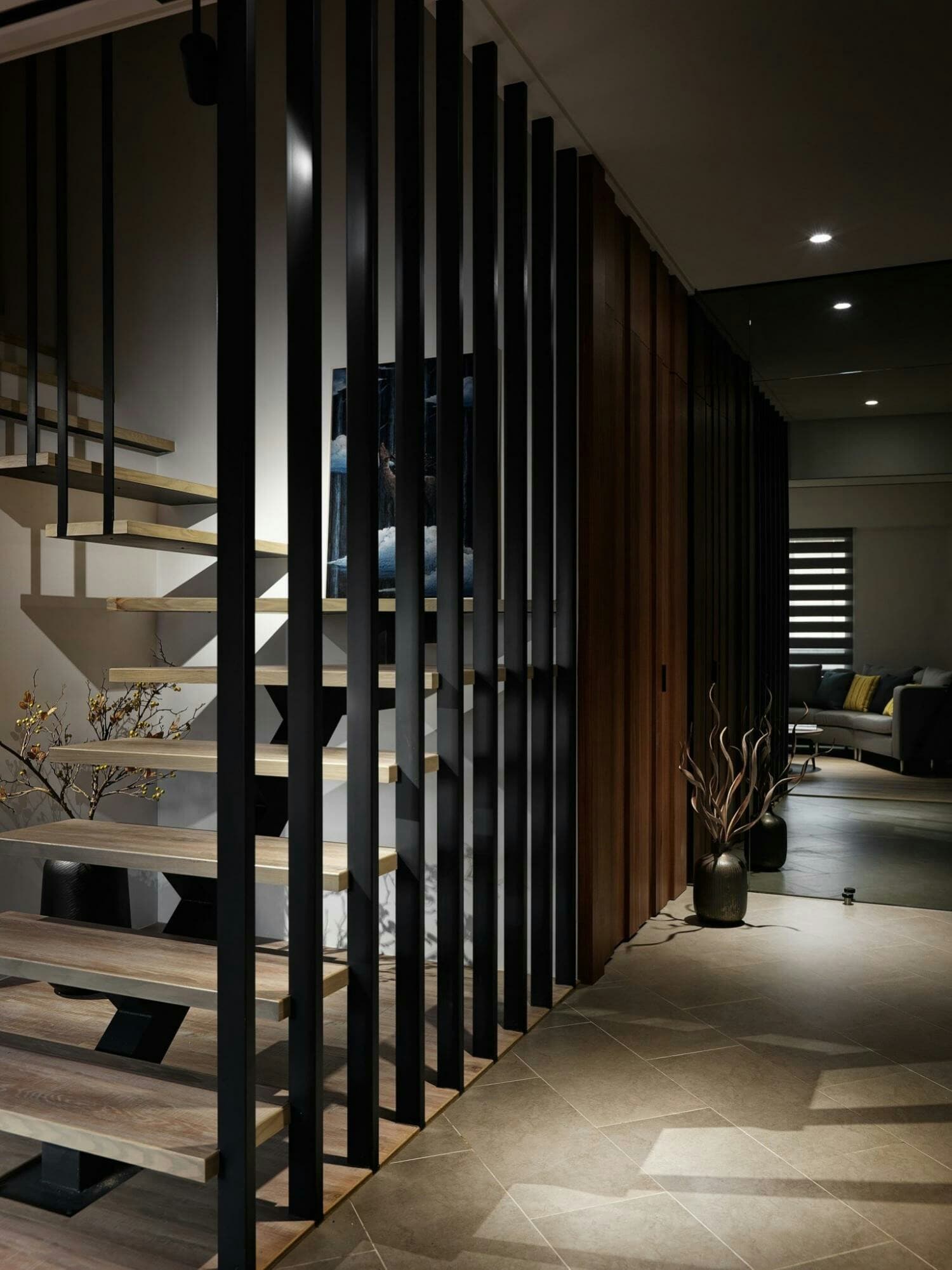 1) 照片展示了一個現代住宅的內部空間，其中有一個木製扶手和黑色金屬扶手的樓梯，以及一個木質牆面