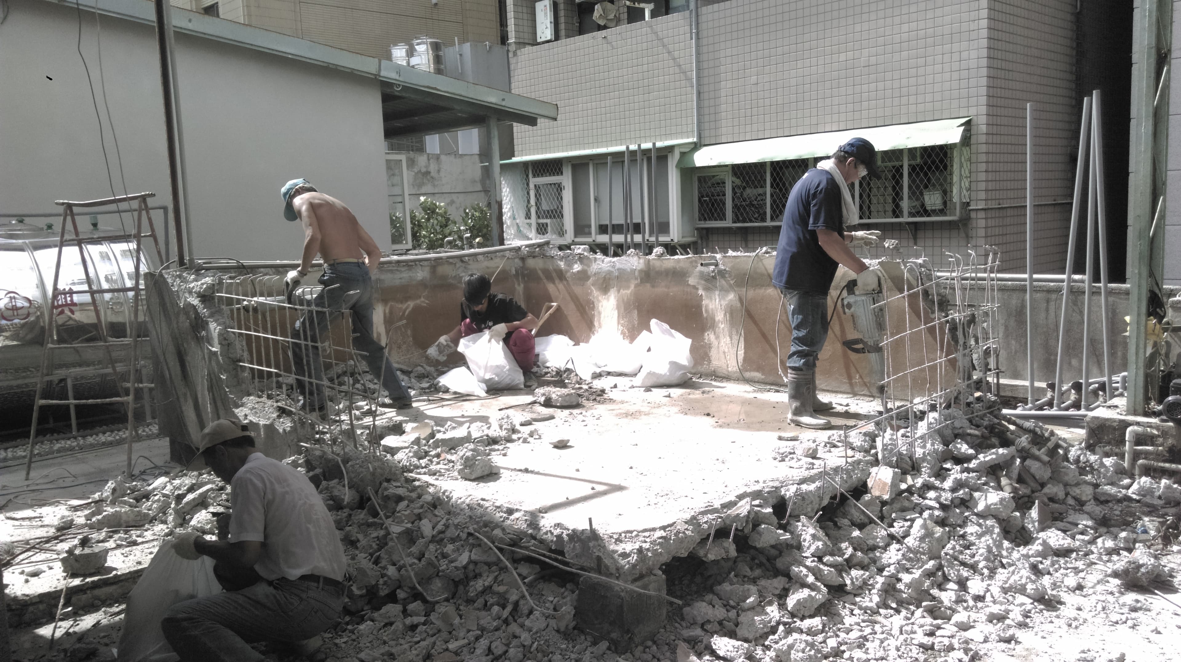 1) 照片中顯示一群建築工人正在拆除一棟建築物的牆壁