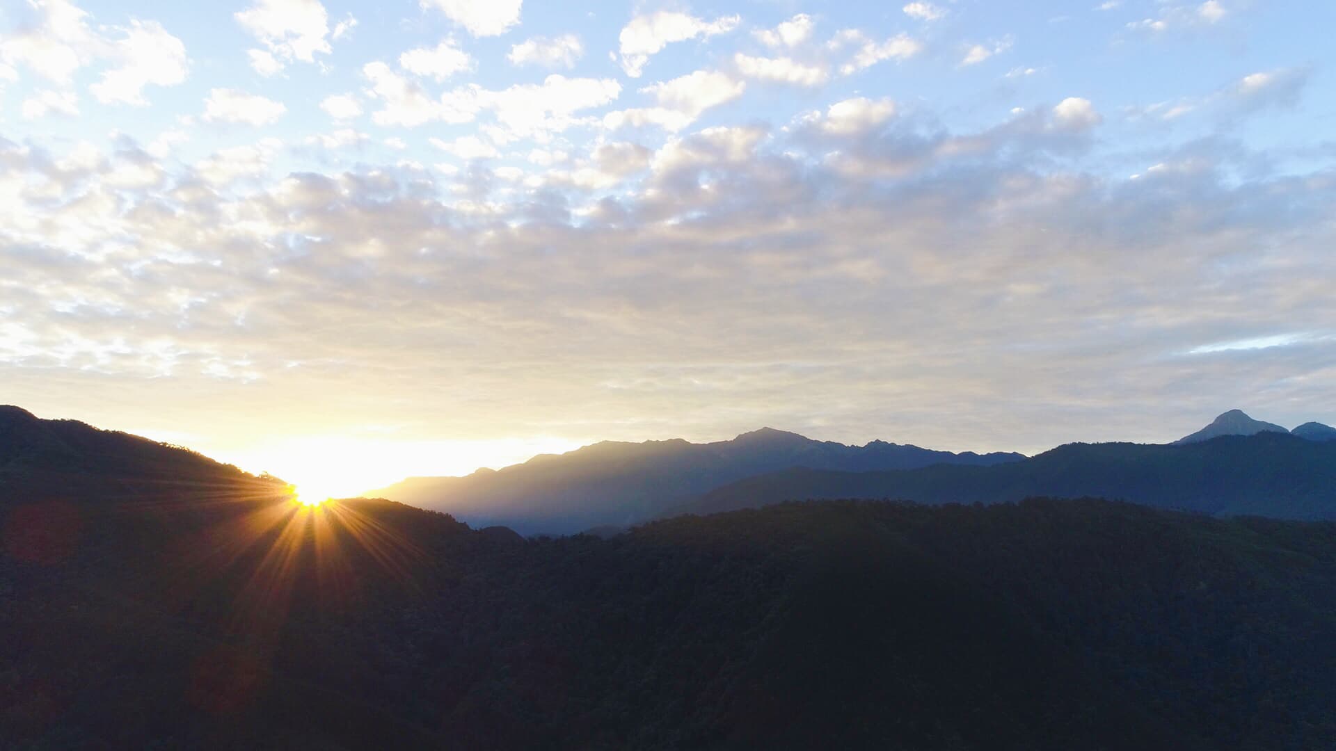 這張「日出」的照片是 山峰輪廓，和金色陽光灑落在雲層中的景象。