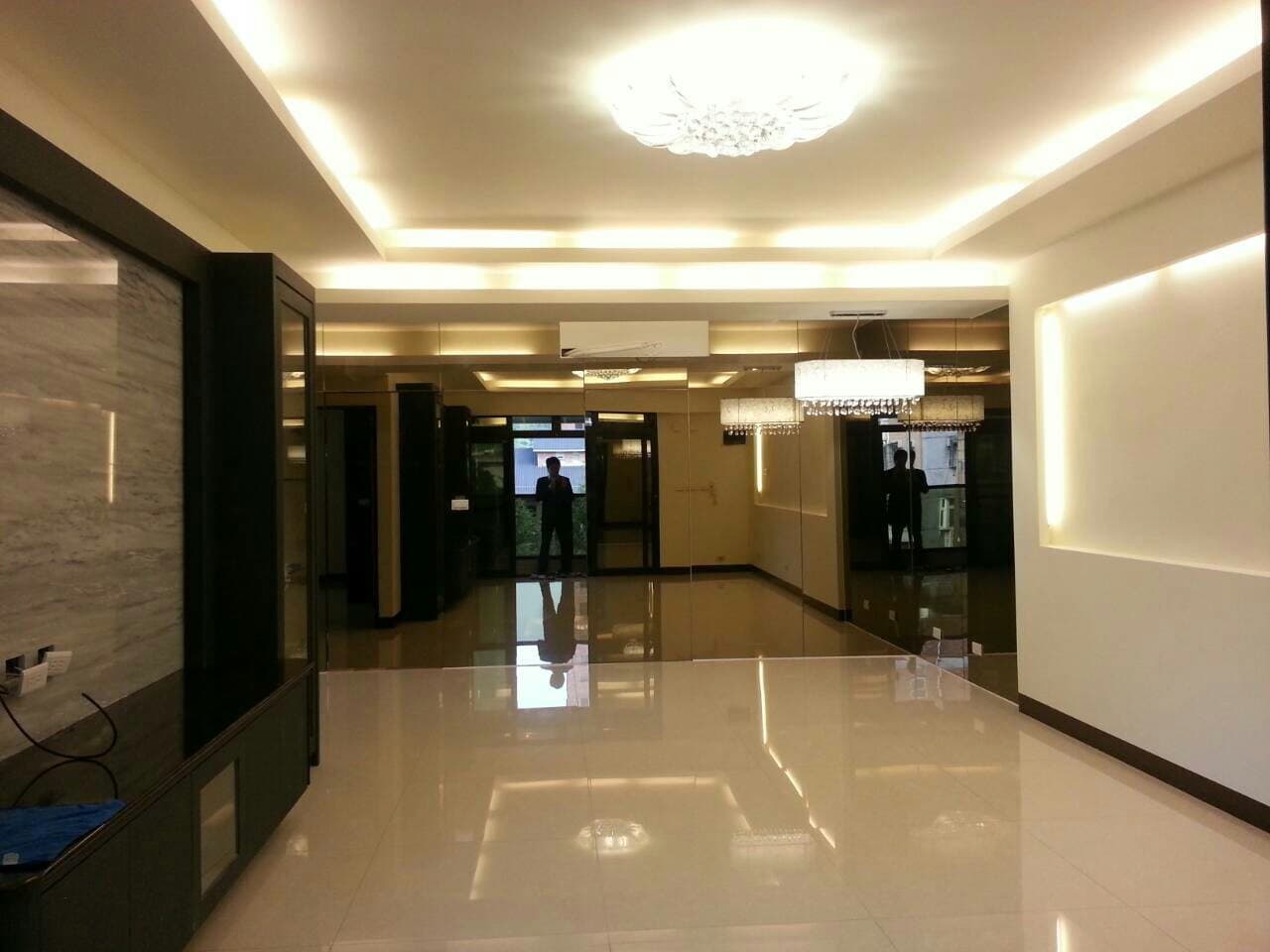 這張照片是一個現代化的客廳，有著明亮的燈光和光滑的瓷磚地板，以及簡約的設計風格。