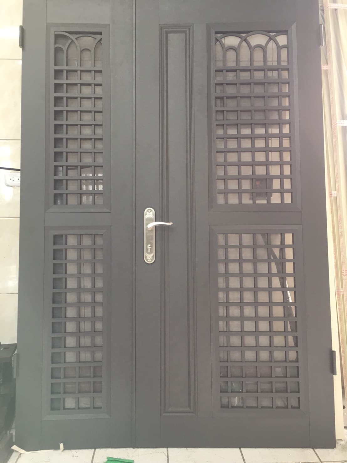 1) 照片中是一扇深灰色的雙門，門上裝有鐵欄杆，且有門把
