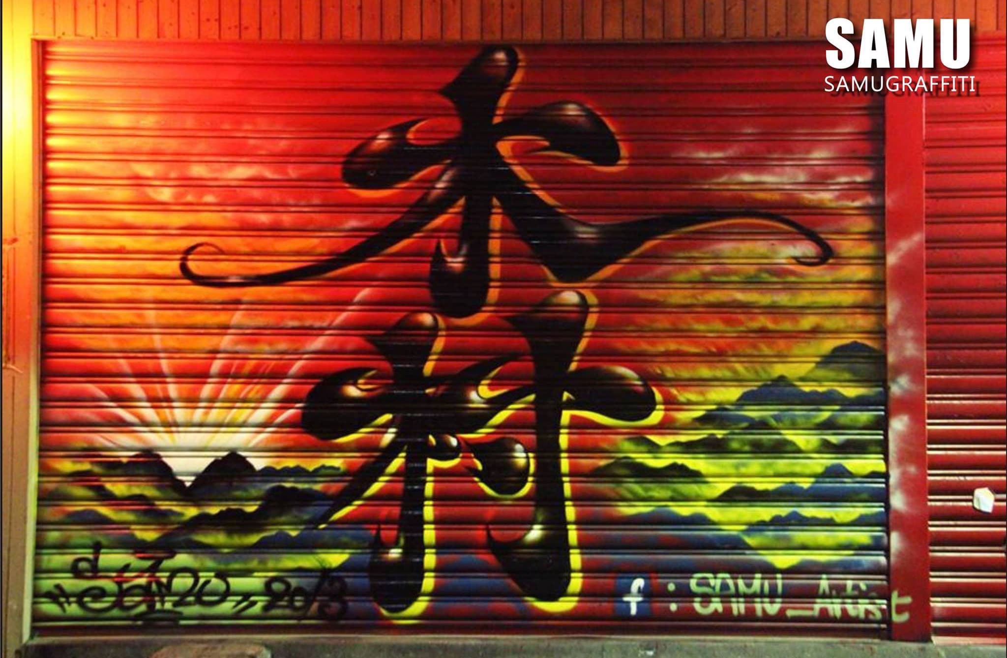 這張「街頭塗鴉」的照片是黑色墨水在紅色捲門上畫的兩個漢字，背景是黃色和綠色的山丘。